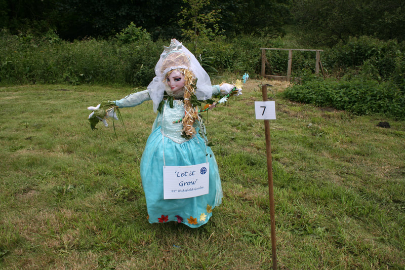 A scarecrow of Elsa with a sign saying "Let it Grow"